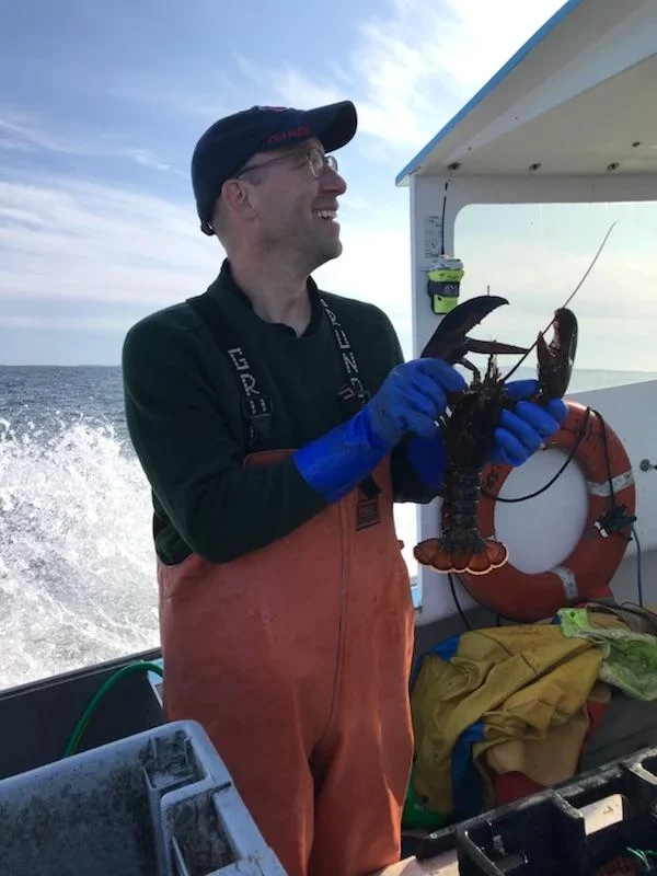 David Cooper holding a lobster on a boat trip